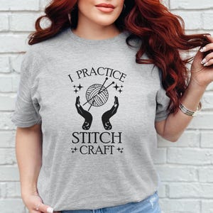 May include: A gray t-shirt with the text "I practice stitch craft" and a graphic of hands holding yarn and knitting needles.