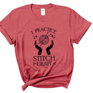 May include: Red short-sleeved t-shirt with black text that reads "I practice stitch craft" and a graphic of two hands holding a ball of yarn with knitting needles.