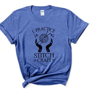 May include: A blue t-shirt with the text "I practice stitch craft" in black lettering. The design features a pair of hands holding a ball of yarn with knitting needles.