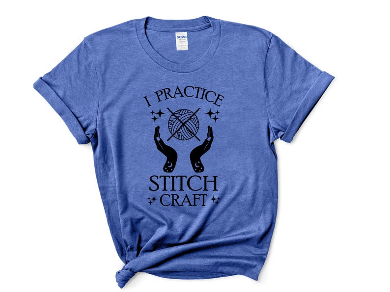 K&ouml;nnte beinhalten: Ein blaues T-Shirt mit dem Text "I practice stitch craft" in schwarzen Buchstaben. Der Text ist umgeben von einem stilisierten Bild eines Wollkn&auml;uels mit zwei H&auml;nden, die es halten.