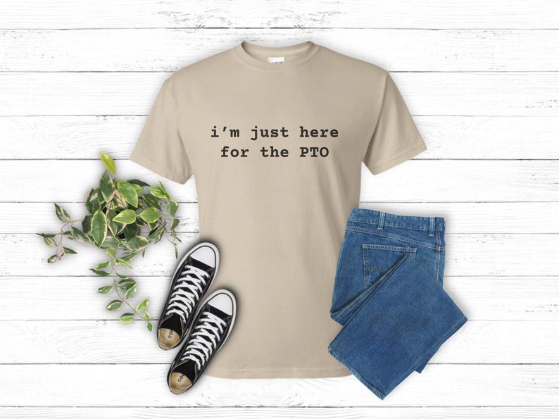 May include: A beige t-shirt with the text "i'm just here for the PTO" printed in black.