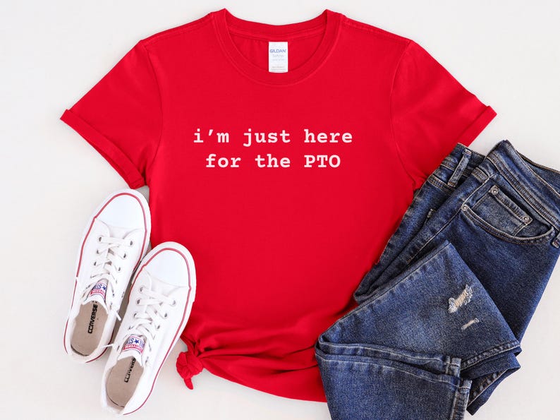 May include: Red t-shirt with white text that reads "i'm just here for the PTO". The shirt is laid flat on a white surface with a pair of white sneakers and blue jeans.