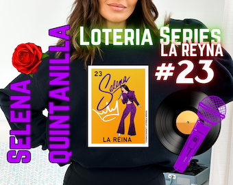 May include: A black sweatshirt with the text "Selena Quintanilla Loteria Series La Reyna #23" printed on it. The sweatshirt features a colorful image of Selena Quintanilla with a microphone and a crown.