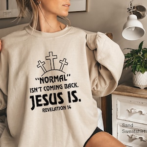 May include: A sand-colored sweatshirt with the text "NORMAL" ISN'T COMING BACK. JESUS IS. REVELATION 14 printed in black.