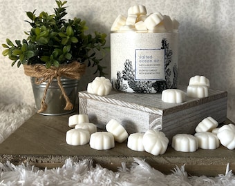 Może przedstawiać: Białe woski w kształcie kwiatu, na tle szklanego słoika z woskami. Słoik ma etykietę z napisem "salted ocean air bath & body works scented candle with essential oils".