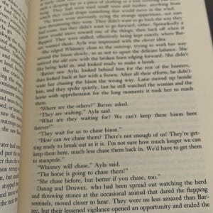 May include: Open book with printed text. The pages are yellowed, and the text is in black. The text is about a group of people chasing bison. The book is open to a specific page.