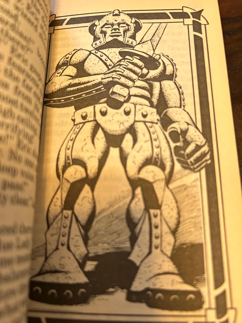 May include: Black and white illustration of a standing armored figure holding a sword. The figure is wearing a helmet and has detailed armor plating. The image is from a book and is surrounded by text.