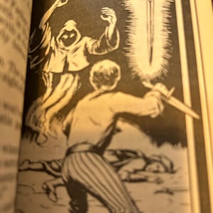 May include: Black and white illustration from a book depicting a fantasy scene. A figure in striped pants and boots is poised with a dagger, facing a glowing sword. A spectral figure with a hooded cloak hovers above, and another figure lies on the ground.