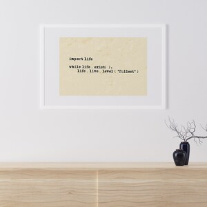 Könnte beinhalten: Ein gerahmter Druck mit beigefarbenem Hintergrund und schwarzem Text, der "import life while life, exist(): life. live. level ("fullest")" lautet.