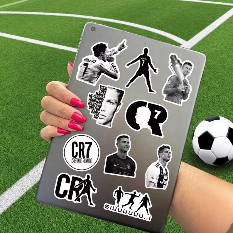 Puede incluir: Un conjunto de pegatinas en blanco y negro con Cristiano Ronaldo en varias poses y el logotipo CR7. Las pegatinas est&aacute;n en una tableta, con un bal&oacute;n de f&uacute;tbol en el fondo. Tambi&eacute;n se ve el texto "Your love makes me strong, your hate makes me unstoppable".