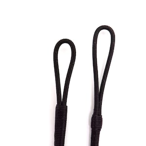 Może przedstawiać: Dwa czarne elastyczne pętle z pojedynczym węzłem na dole każdej pętli.