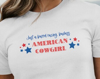 May include: White t-shirt with red, white and blue stars and the text "Just a barrel racing, badass American Cowgirl".