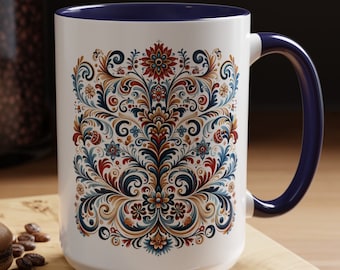Könnte beinhalten: Weiße Keramiktasse mit blauem Rand und Henkel. Die Tasse zeigt ein farbenfrohes Blumenmuster in Rot-, Blau-, Gold- und Grüntönen.