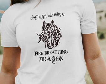 May include: White t-shirt with a black graphic of a horse's head with flames and the text "Just a girl who rides a fire breathing dragon."