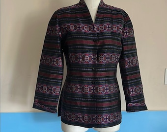 May include: A patterned jacket with a mandarin collar and long sleeves. The jacket features a black background with horizontal stripes in burgundy, purple, and blue. It is buttoned up and displayed on a mannequin.