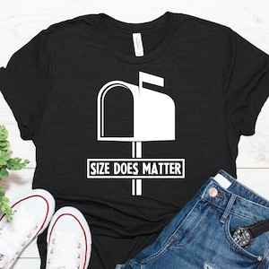 Puede incluir: Camiseta negra con un gr&aacute;fico de buz&oacute;n blanco y el texto "SIZE DOES MATTER". La imagen incluye zapatillas blancas y pantalones cortos de mezclilla. La camiseta est&aacute; hecha de un material suave y c&oacute;modo.