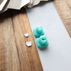 Puede incluir: Dos puntas de auriculares de silicona azul turquesa y dos puntas de auriculares blancas sobre una superficie de madera.