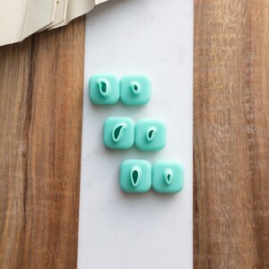 May include: Six turquoise blue silicone fondant cutters shaped like a teardrop. The cutters are arranged in two rows of three.