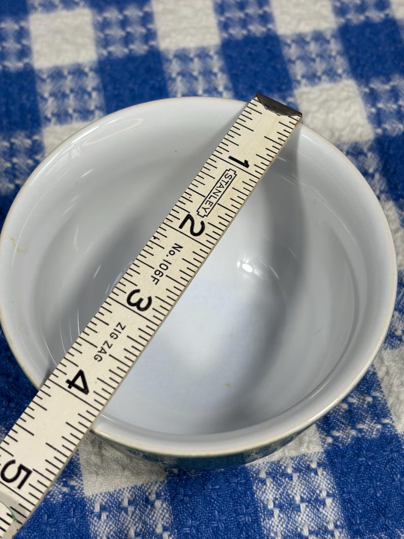 Peut inclure: Un bol en c&eacute;ramique blanche avec un int&eacute;rieur lisse, vu d'en haut. Une r&egrave;gle pliante Stanley No. 106F Zig Zag est plac&eacute;e sur l'ouverture, indiquant un diam&egrave;tre d'environ 10,2 cm pour le bord du bol.