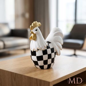 May include: A decorative rooster figurine featuring a white head and neck with gold accents on the comb and wattle. The body is decorated with a black and white checkered pattern, and the tail feathers are solid white with gold-painted edges.