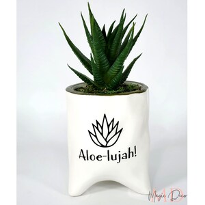 May include: White ceramic planter with a green succulent plant. The planter has a black outline of a succulent and the text "Aloe-lujah!"