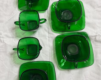 May include: Set of five green glass teacups and saucers. The cups and saucers are square shaped with a raised design on the bottom.