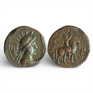 May include: Two antique bronze coins. One coin features a profile of a person with a laurel wreath and sun rays. The other coin depicts a horse and tree. The coins have a weathered appearance.