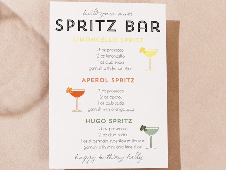 Peut inclure: Une carte imprimable avec des instructions pour faire trois spritz diff&eacute;rents : Limoncello Spritz, Aperol Spritz et Hugo Spritz. Chaque recette comprend les ingr&eacute;dients et les garnitures. La carte indique &eacute;galement "build your own SPRITZ BAR" et "happy birthday kelly".
