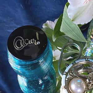 Botella vintage/antigua de vidrio soplado a mano color verde azulado con tapa negra