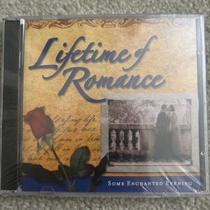 May include: A CD case with a yellow background and a blue and white border. The title "Lifetime of Romance" is written in a large, decorative font. The image on the front of the case shows a couple standing on a balcony, with a rose and leaves in the foreground. The text "Some Enchanted Evening" is written at the bottom of the case.