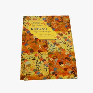 Könnte beinhalten: Ein Buch mit dem Titel "Giftwraps by Artists: Kimono Japanese Designs" mit einem farbenfrohen Blumenmuster in Orange-, Gelb-, Blau- und Grüntönen. Das Cover des Buches zeigt ein lebendiges Design mit verschiedenen Blumen- und Vogelmotiven.