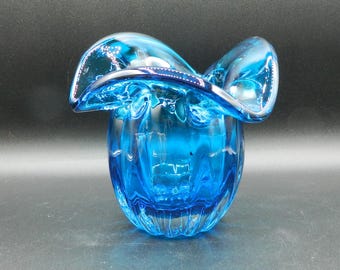 Könnte beinhalten: Eine blaue Glasvase mit einem gekräuselten oberen Rand und einem strukturierten Körper. Die Vase ist aus klarem Glas mit einer blauen Tönung.