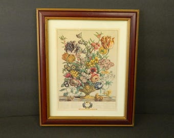 Puede incluir: Impresión floral enmarcada con un vibrante ramo de flores en un jarrón decorativo. La impresión tiene un borde dorado y está encerrada en un marco de madera marrón oscuro. Las flores incluyen tulipanes, rosas y otras flores coloridas.