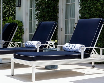 Könnte beinhalten: Zwei weiße Liegestühle mit blauen Kissen und weißen Handtüchern, auf denen "POOL" steht. Die Stühle stehen auf einer weißen Terrasse mit einem kleinen Tisch und einem Glas Limettensaft.