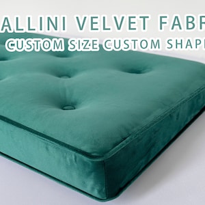 May include: A green velvet cushion with button tufting. The cushion is rectangular and has a stitched edge. The text "VALLINI VELVET FABRIC CUSTOM SIZE CUSTOM SHAPE" is visible at the top of the image.