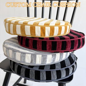 May include: Four custom chair cushions stacked on a black chair. The cushions feature striped patterns in yellow and white, red and black, gray and white, and black and gray. The text "CUSTOM CHAIR CUSHION" is displayed at the top.