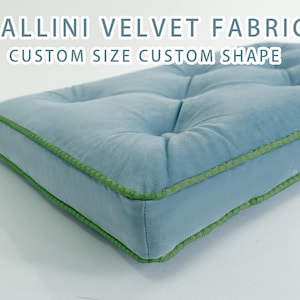 May include: A square, light blue velvet cushion with a green trim. The cushion has a tufted design with button accents. Text on the image reads "VALLINI VELVET FABRIC CUSTOM SIZE CUSTOM SHAPE."