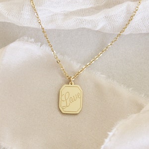 May include: A gold chain necklace with a square pendant that says "Love" in cursive.