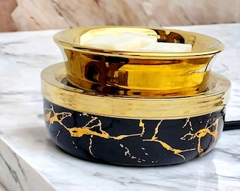 May include: A black and gold ceramic wax warmer with a marble pattern. The warmer has a top bowl for wax melts and a bottom bowl for a tealight.