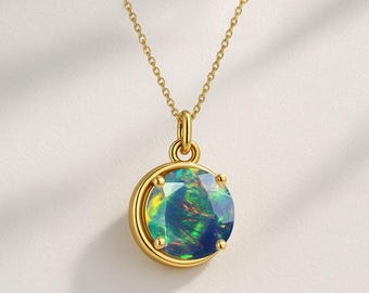 May include: A gold-colored necklace featuring a round pendant with a vibrant, iridescent opal gemstone. The opal displays a mix of green, blue, and yellow hues. The pendant is set in a gold bezel and hangs from a delicate gold chain.