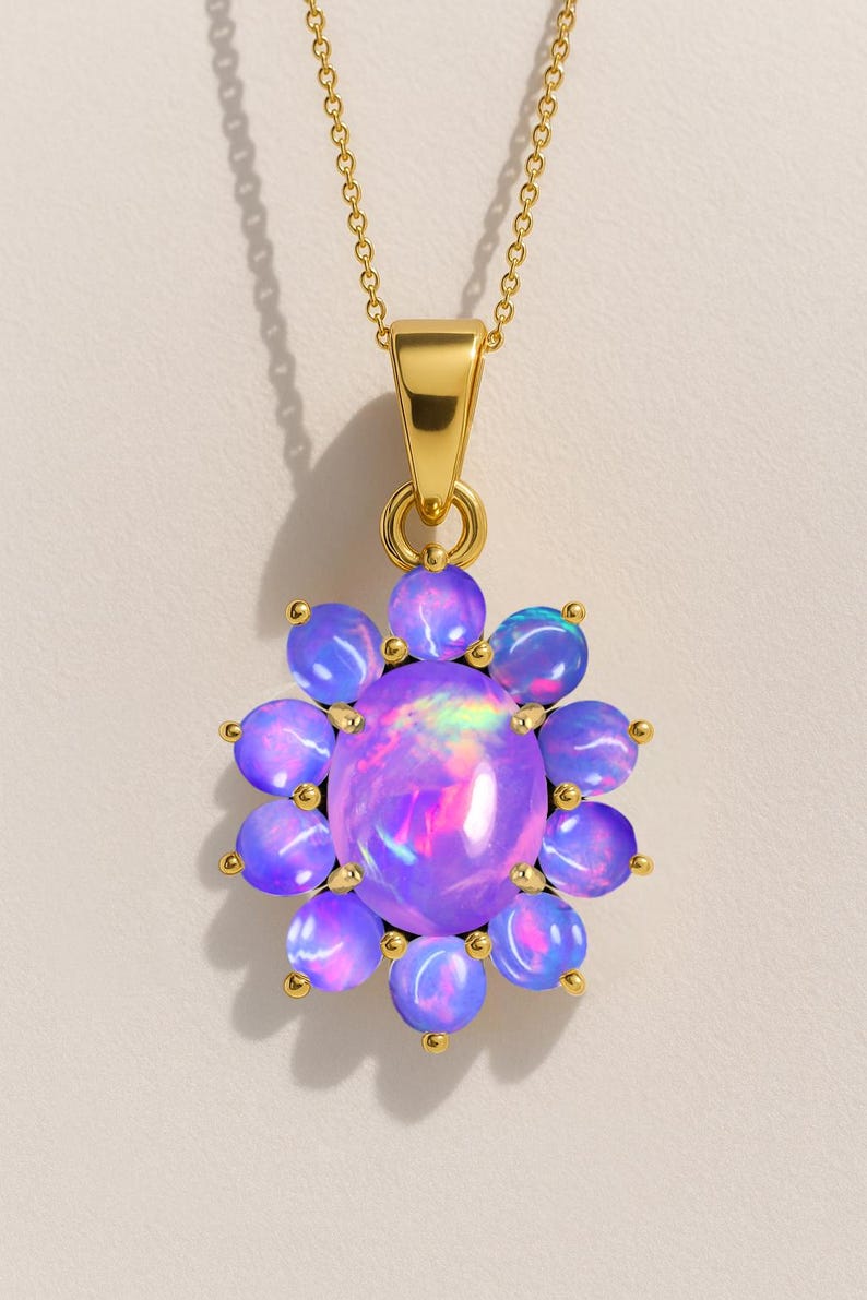 May include: A gold-toned necklace featuring a pendant with a large, oval, iridescent opal stone at the center, surrounded by smaller, round, purple-blue opals. The pendant is flower-shaped and hangs from a delicate chain.
