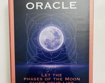 Może przedstawiać: Zapakowana talia kart zatytułowana "THE MOON ORACLE" z grafiką pełni księżyca. Okładka ma ciemnoniebieskie tło z białym tekstem i różową obwódką. Widoczny jest również tekst "LET THE PHASES OF THE MOON GUIDE YOUR LIFE".