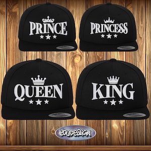 Könnte beinhalten: Vier schwarze Baseballkappen mit weiß gesticktem Text und Kronendesigns. Die Kappen tragen die Aufschrift "Prinz", "Prinzessin", "Königin" und "König".