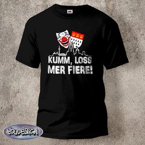 Puede incluir: Camiseta negra con un diseño blanco. El diseño incluye una máscara sonriente, un escudo con tres coronas y el texto "Kumm, loss mer fiere!" en blanco, junto con una silueta de paisaje urbano.