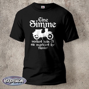 Op de afbeelding: Zwart t-shirt met een witte afbeelding van een scooter en Duitse tekst. De tekst luidt "Eine Stimme verliert kein Öl sie markiert ihr Revier."