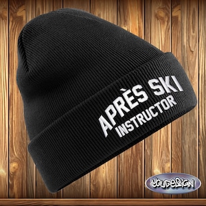 Peut inclure: Un bonnet noir en tricot avec les mots "APRÈS SKI INSTRUCTOR" brodés en blanc. Le chapeau est fait d'une matière douce et chaude, parfait pour le froid. Le design est simple et élégant.