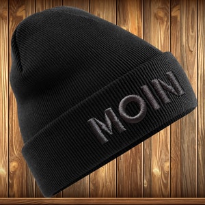 May include: Black beanie with the word "MOIN" embroidered in white on the front.