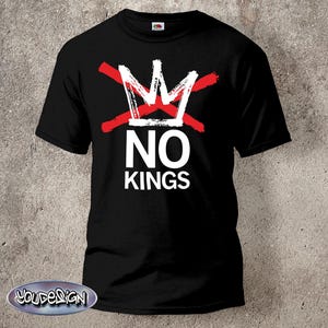 Könnte beinhalten: Schwarzes T-Shirt mit einem weißen Kronen-Design, das von zwei roten Linien durchkreuzt wird. Darunter stehen die weißen Worte "NO KINGS". Das Shirt besteht aus einem weichen Material.