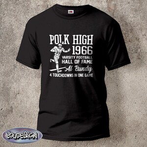 Könnte beinhalten: Schwarzes T-Shirt mit weißem Text und einer Footballspieler-Grafik. Der Text lautet "POLK HIGH 1966 VARSITY FOOTBALL HALL OF FAME Al Bundy 4 TOUCHDOWNS IN ONE GAME". Das Shirt hat ein klassisches Design.