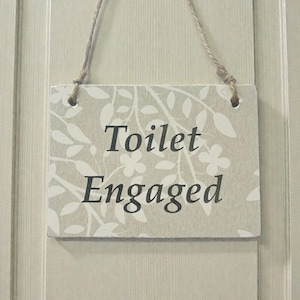 以下が含まれることがあります： 白のセラミックマグカップ、黒いハンドルと手書き風の「But First, Coffee」の文字。マグカップは白い表面に置かれています。マグカップの高さは約10cmです。